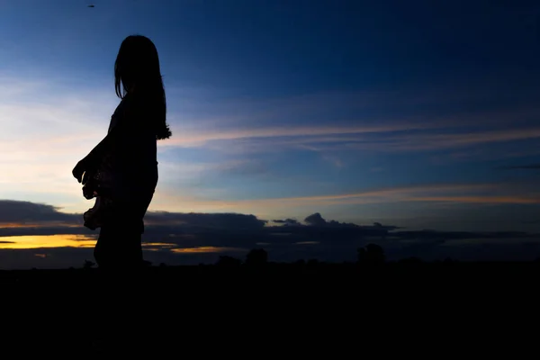 Silhouette einer Frau, die bei Sonnenuntergang oder Sonnenaufgang posiert — Stockfoto