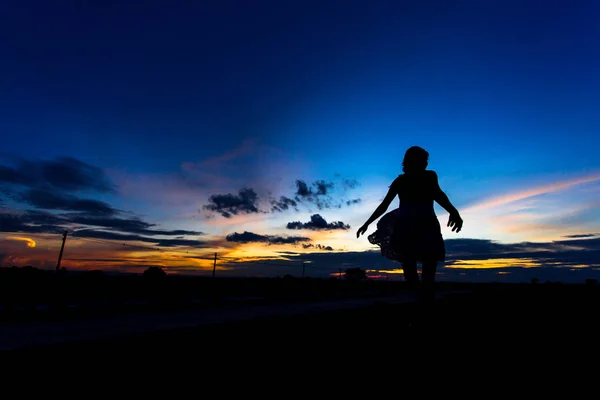 Silhueta de mulher posando ao pôr do sol ou ao nascer do sol — Fotografia de Stock