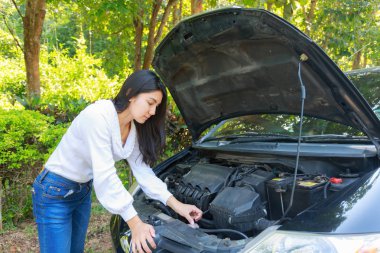 Asyalı kadın açık kukuleta ile kırık bir araba ile.