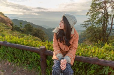 Asyalı bir kadın dağın tepesinde dinleniyor. 