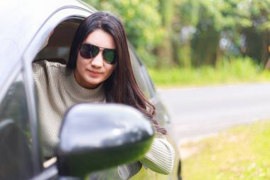 Asyalı kadın arabanın penceresinden dışarı çıkar.