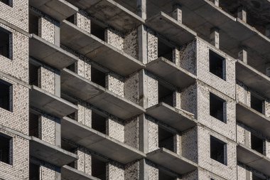 İnşaat halindeki bir tuğla binanın duvarı. Yeni bir apartmanın pencere ve balkonları.