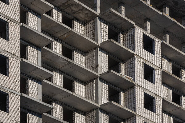 The wall of a brick building under construction. Windows and balconies of a new apartment building. Background.