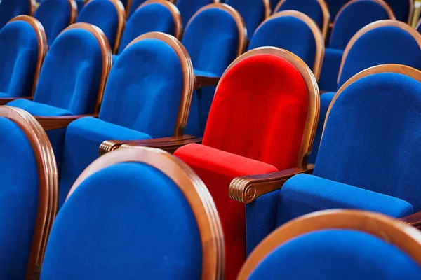 Red chair among the blue seats. Special or VIP seat in the meeting room