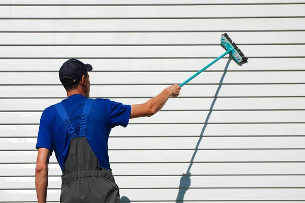 White man in overalls washes the wall with a brush. — Stock Photo, Image