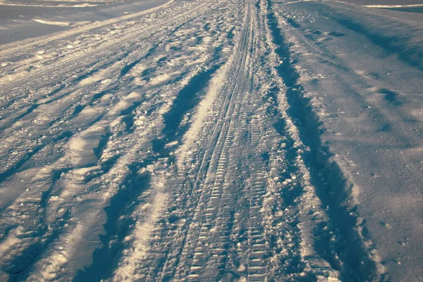 Sporen van voertuigen en mensen op de besneeuwde winterweg. — Stockfoto