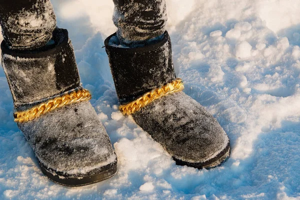 Mujeres negras uggs con una cadena dorada. Zapatos de invierno de moda en las piernas de una chica. Protección contra inviernos helados . — Foto de Stock