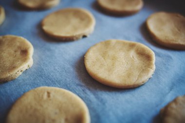 Kurabiye veya zencefilli ekmek yapmak için yuvarlak hamur parçaları kağıt üzerinde. Kendi ellerinle ev yapımı pişirme. Üst görünüm