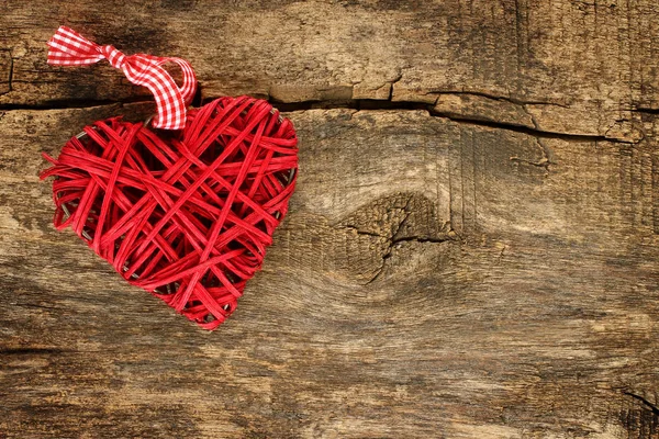 Červená proutěné srdce na dřevěné pozadí — Stock fotografie