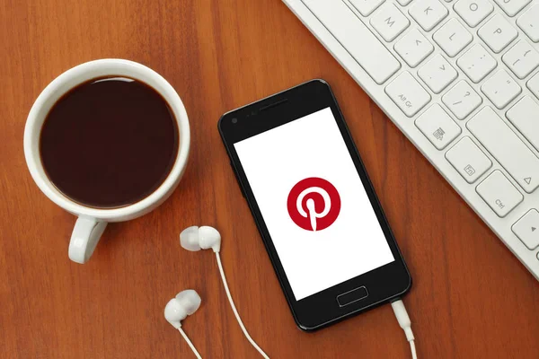 Tasse Kaffee und Smartphone mit Pinterest-Logo auf dem Bildschirm — Stockfoto