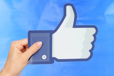 El Facebook logosu mavi kağıt arka plan üzerinde tutar.