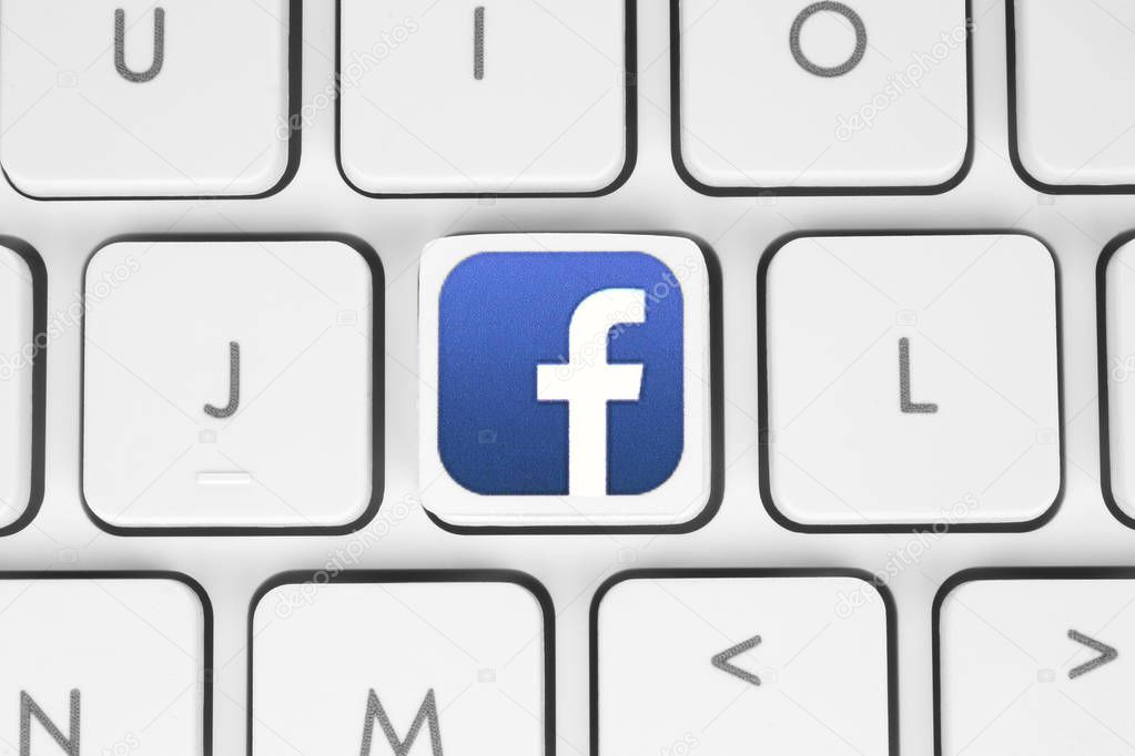 Kiev, Ukraine - May 06, 2016: Facebook logo printed on paper and placed on white computer keyboard. Facebook is a well-known social networking service