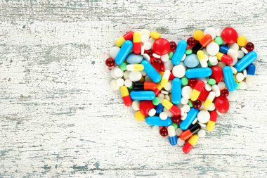 Eski ahşap arka plan üzerinde kalp şeklinde renk hapları