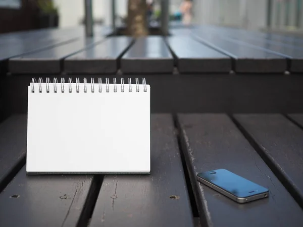 Livro nota branca em branco e telefone inteligente — Fotografia de Stock