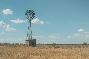 Old windmill at blue cloudy sky clipart