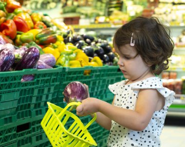 Süpermarkette patlıcan alışverişi yapan çocuk. Meyve almak için kavram