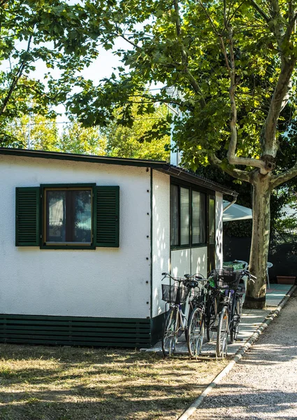 Liten vit bungalow på campingplatsen. Cyklar framför bungalow. — Stockfoto