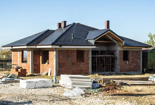 Construyendo una nueva casa de ladrillo con techo negro. Pequeñas casas en contra — Foto de Stock