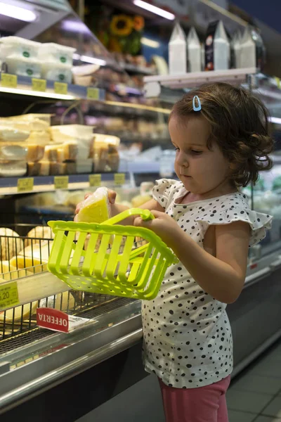 Niña comprando queso en el supermercado. Niño mantenga pequeño baske Imagen de archivo