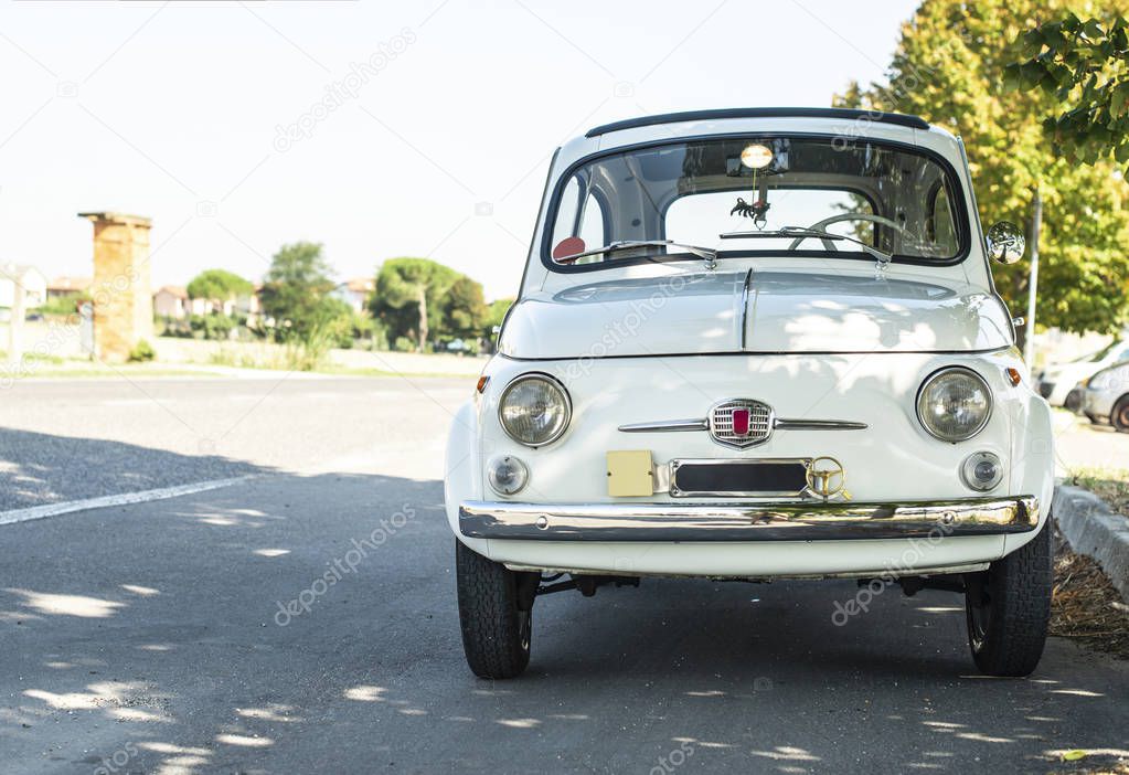 White small vintage car on the street. No people. 