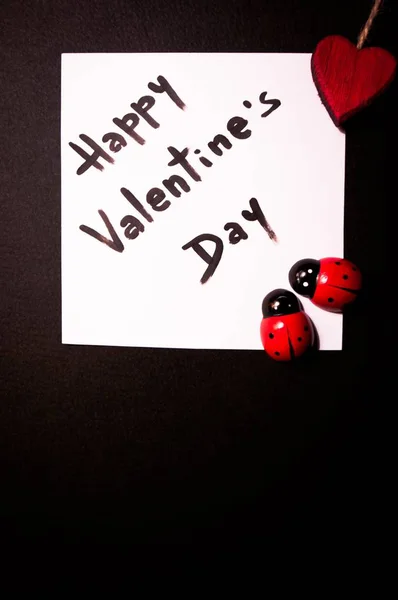 Valentine's card displayed with a red heart and two small toy ladybugs — Stock Photo, Image