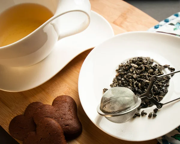 bir fincan çay ile Çikolatalı çerezleri hizmet yanında yeşil çay yaprakları