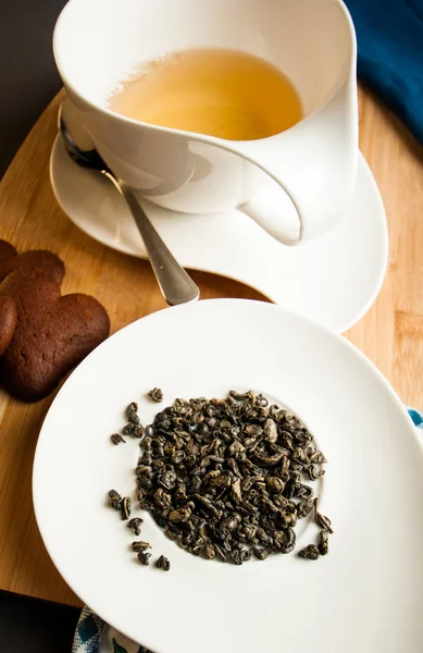 bir fincan çay ile Çikolatalı çerezleri hizmet yanında yeşil çay yaprakları