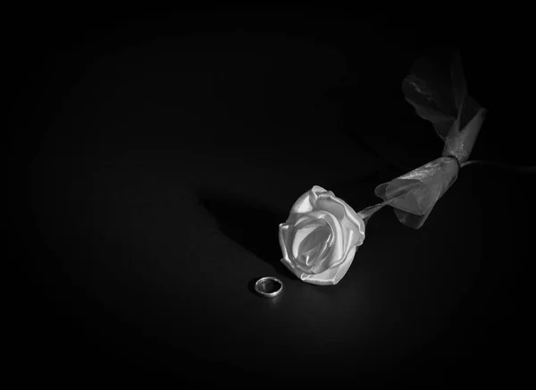 siyah bir arka plan üzerine gül beyaz bir kumaş ile görüntülenen bir altın alyans, siyah beyaz fotoğraf