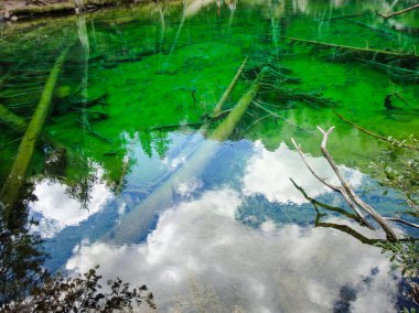Le nuovle del cielo blu riflesse nelle acque verdi del lago alpino
