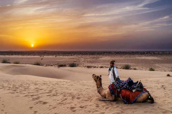 Hombre de pie cerca de camello en el desierto — Foto de Stock