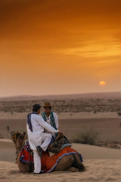 Два человека и верблюд в пустыне — стоковое фото
