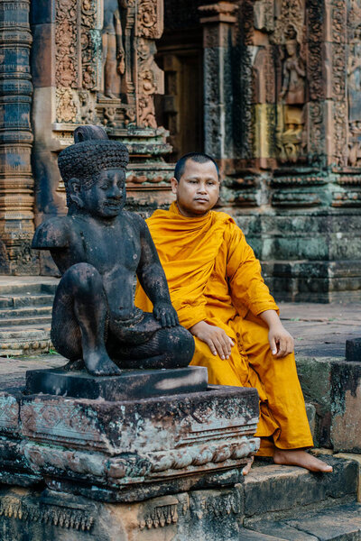 Monk sitting near sculpture