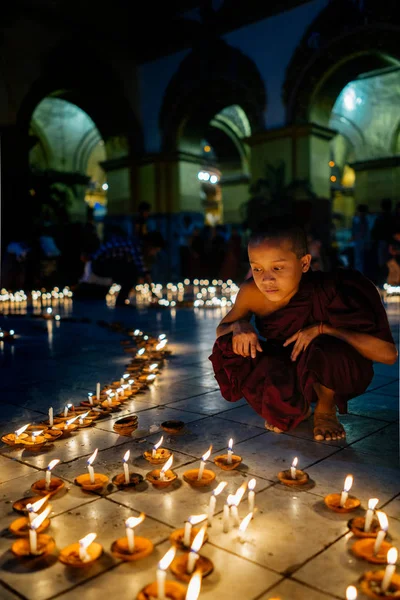 Piccolo monaco seduto vicino all'ornamento delle candele — Foto Stock