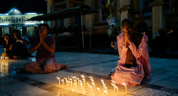 Buddhist monk praying near burning candles — Stock Photo, Image