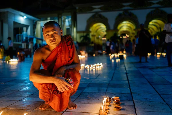 Boeddhistische monnik zitten in de buurt van kaarsen sieraad — Stockfoto