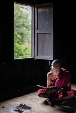 Açık kitap ile oturan Budist rahip