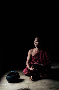 Açık kitap ile oturan Budist rahip