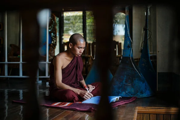 Açık kitap ile halı üzerinde oturan keşiş