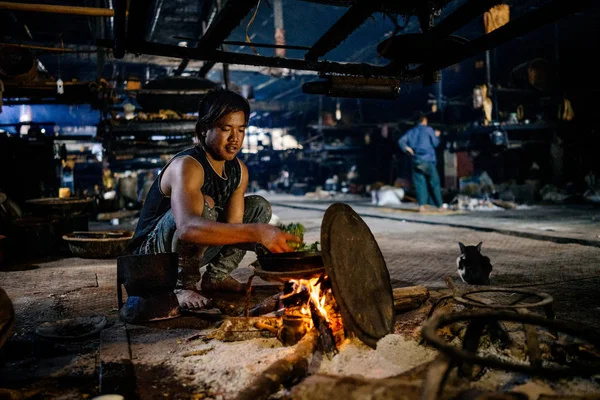 Man cooking on open fire in village hut — Stock Photo, Image