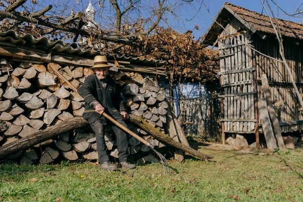 Man with pitchfork leaning on firewood