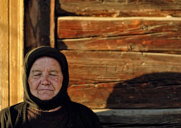 Idős asszony ül, csukott szemmel — Stock Fotó