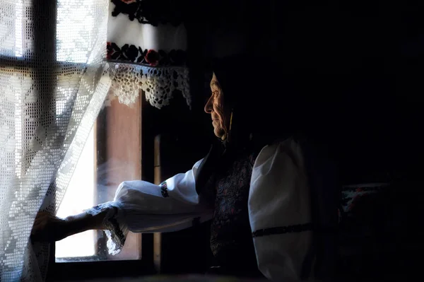 Bufanda de mujer en la cabeza mirando por la ventana — Foto de Stock