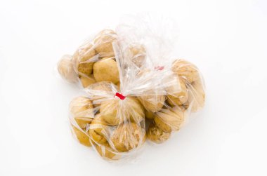 Beyaz arka planda plastik poşette taze patates.