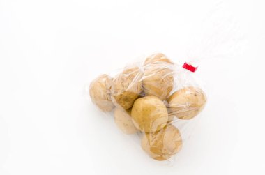 Beyaz arka planda plastik poşette taze patates.