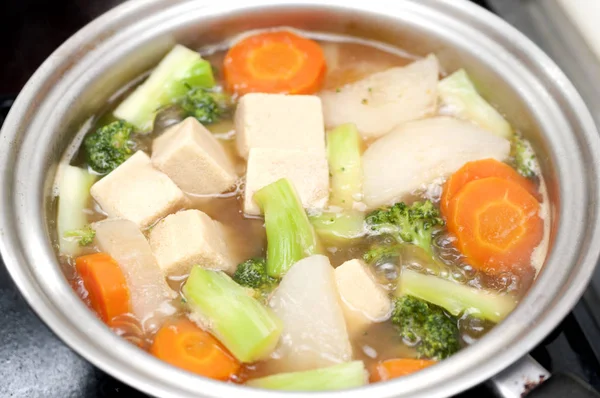 Koya-tofu (dondurulmuş tofu) ve bir tencerede kaynamış sebzeler..