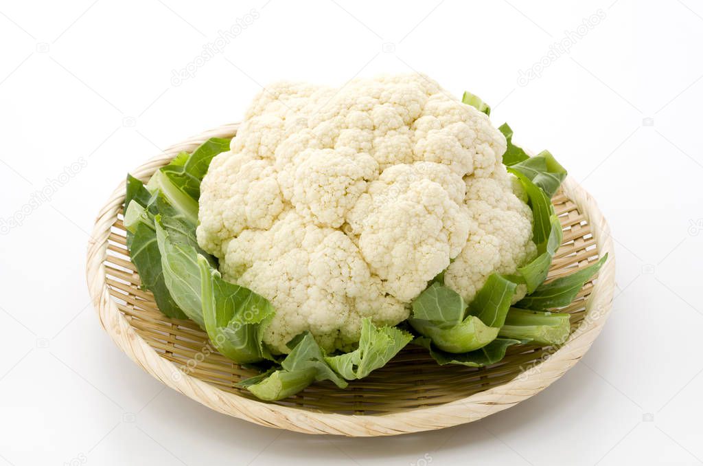 Fresh cauliflower on bamboo sieve on white background