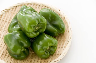 Beyaz arka planda bambu elek üzerine dolma biber.