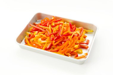 Alüminyum tepside kırmızı, turuncu ve sarı dolma biber beyaz arkaplanda.