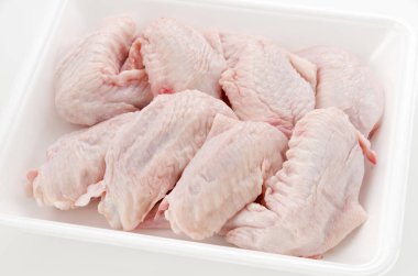 Beyaz plastik bir kabın içinde çiğ ve çiğ tavuk kanadı.