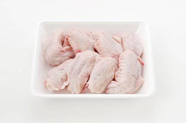 Beyaz plastik bir kabın içinde çiğ ve çiğ tavuk kanadı.